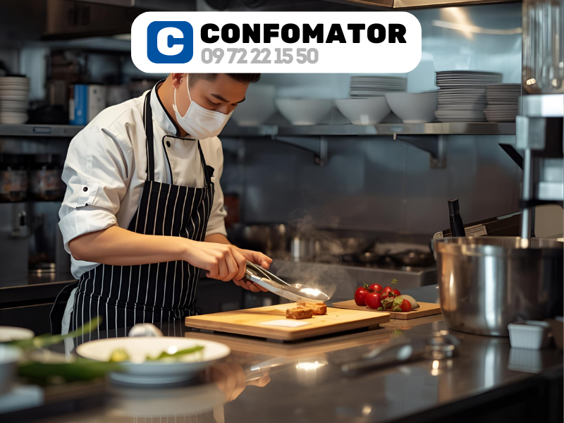 Chef professionnel ayant obtenu les certificats de conformité travaillant dans une cuisine de restaurant moderne avec hotte d'extraction professionnelle certifiée, illustrant les normes d'hygiène et de sécurité alimentaire HACCP